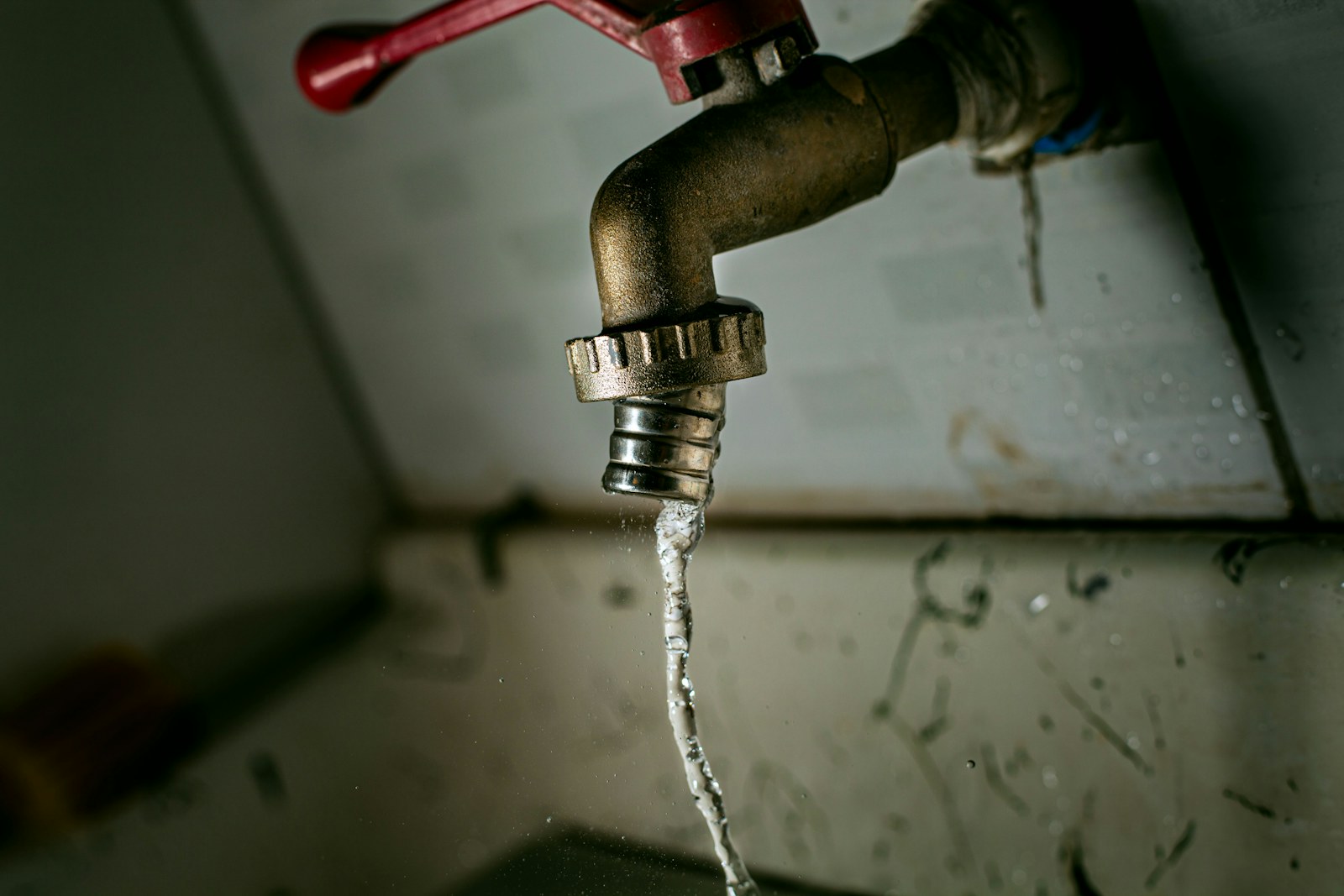 Water gushing from an old brass faucet under a sink