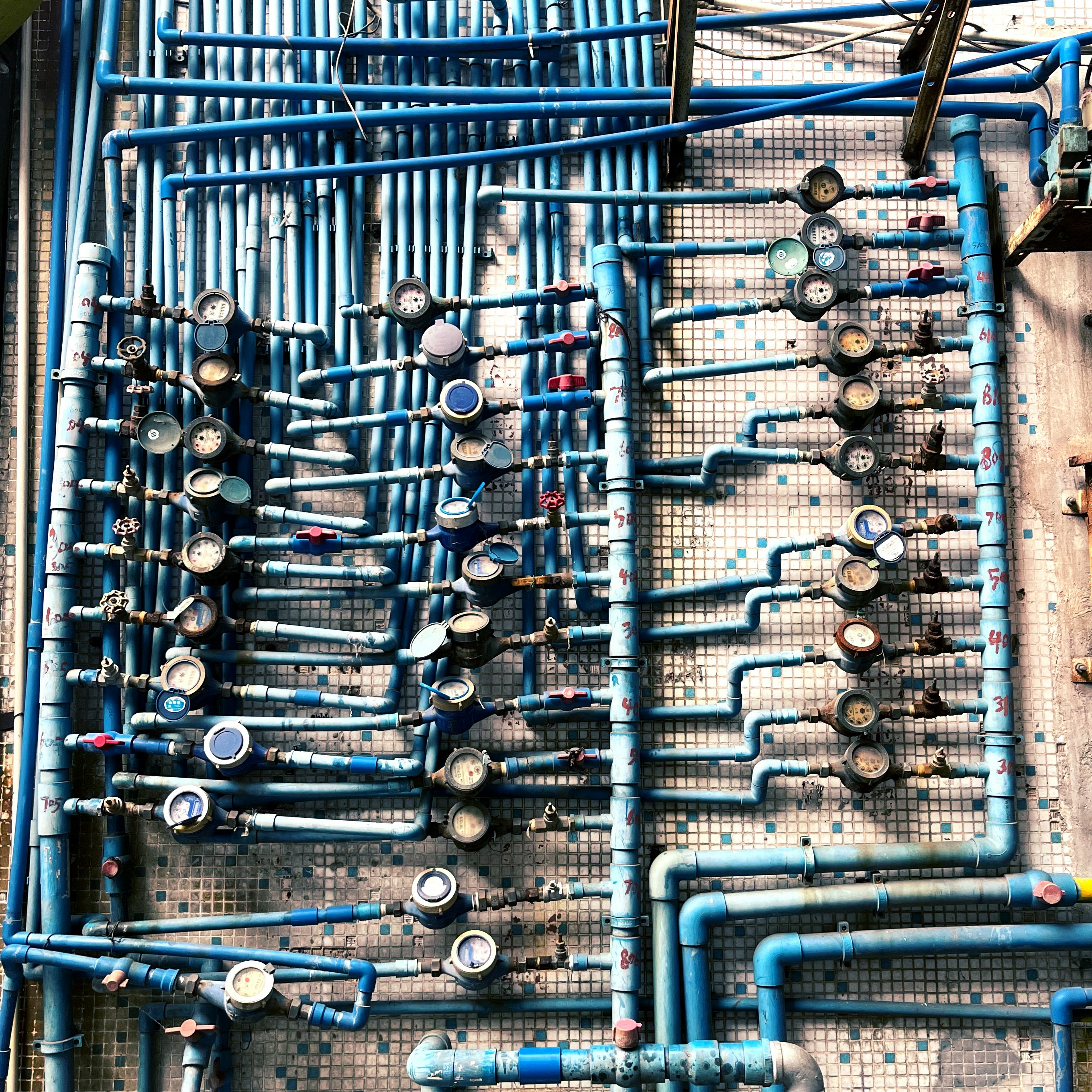 Wall of blue water supply pipes and shut-off valves in an apartment plumbing riser