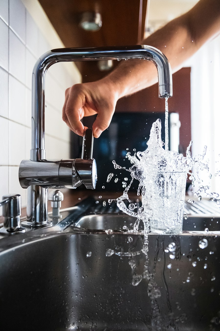 Chrome kitchen faucet running water into a stainless steel sink
