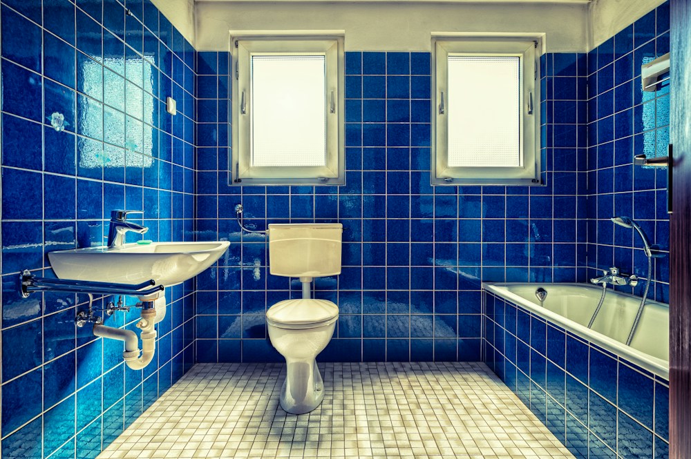 Before: dated blue-tiled bathroom with an old toilet and tub in a Park Slope pre-war apartment