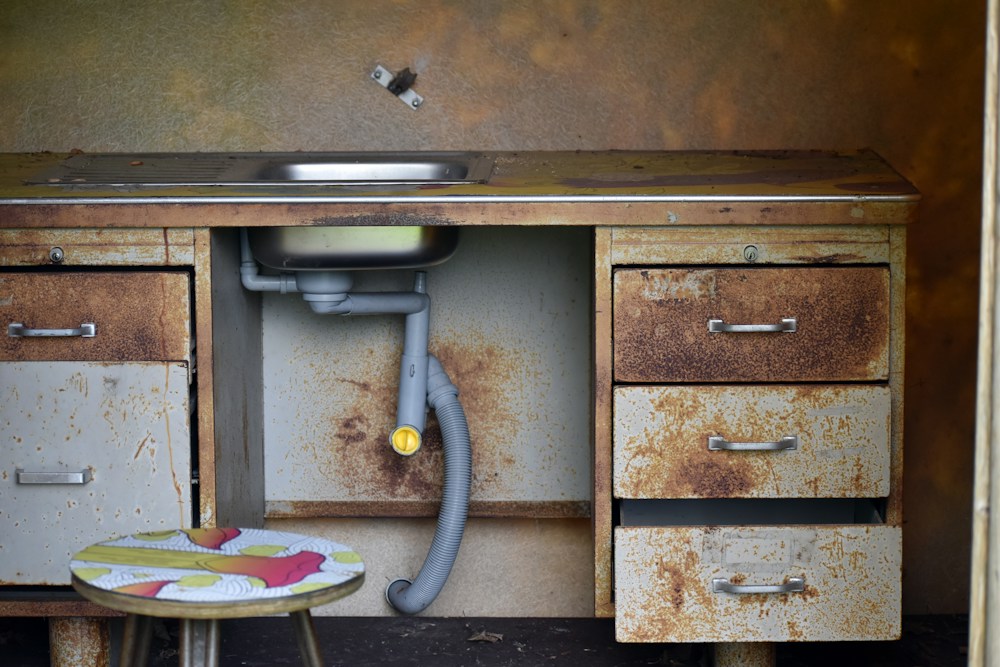 Before: corroded sink trap and rusted cabinet under an old Williamsburg kitchen sink